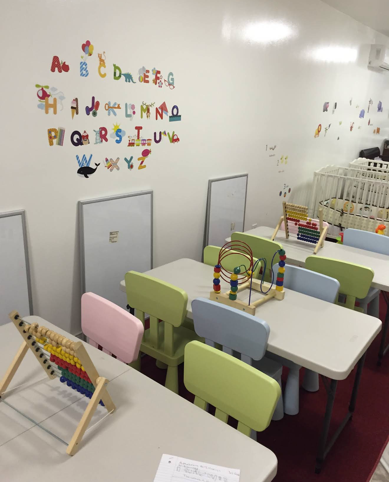 Suki Daycare classroom with child-sized tables, chairs, alphabet wall and learning materials
